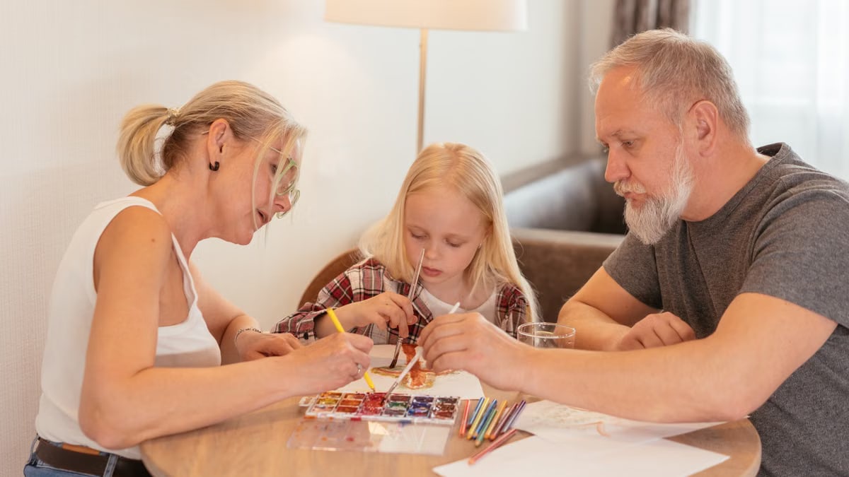 A family of three enjoying creative time with painting and drawing at home.
